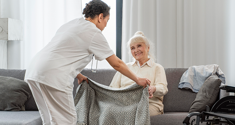 caregiver assisting elderly woman with blanket