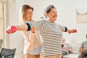 Caregiver assisting senior woman with light exercise using dumbbells, home care Hoffman Estates, IL