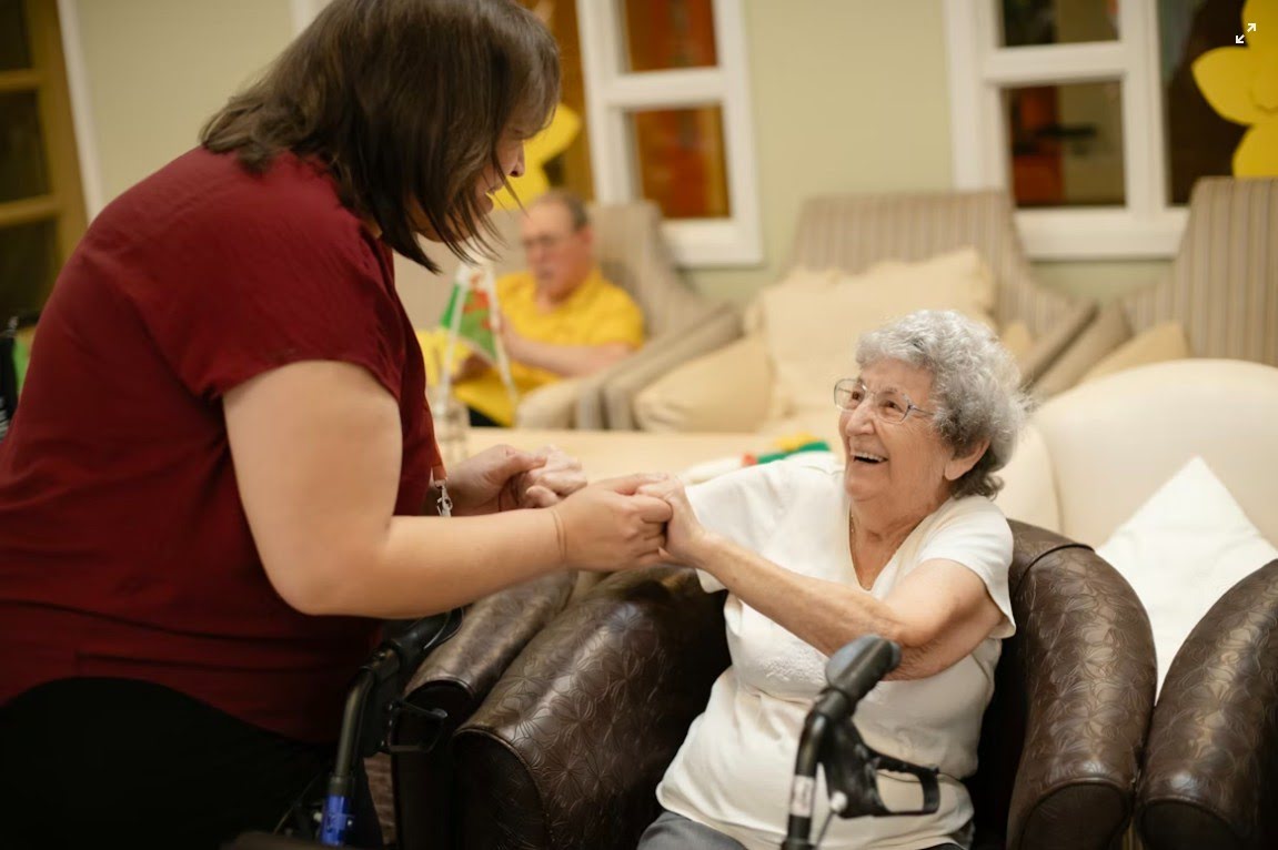 Caregiver holding hands with a smiling senior during in-home care support for Schaumburg, IL families